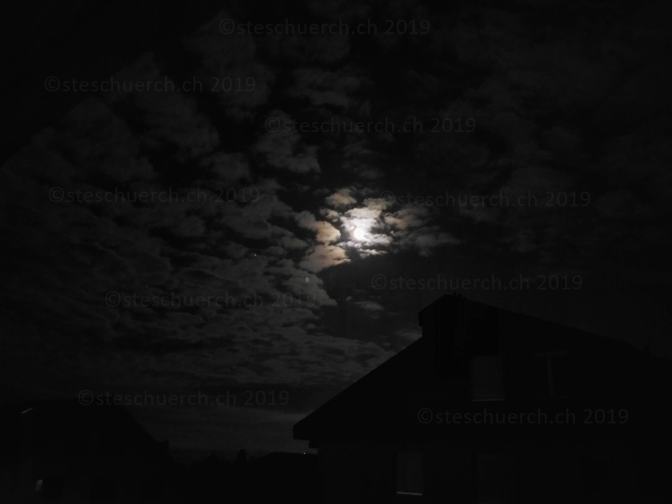 Hell leuchtender fast Vollmond hinter Wolken in der Nacht